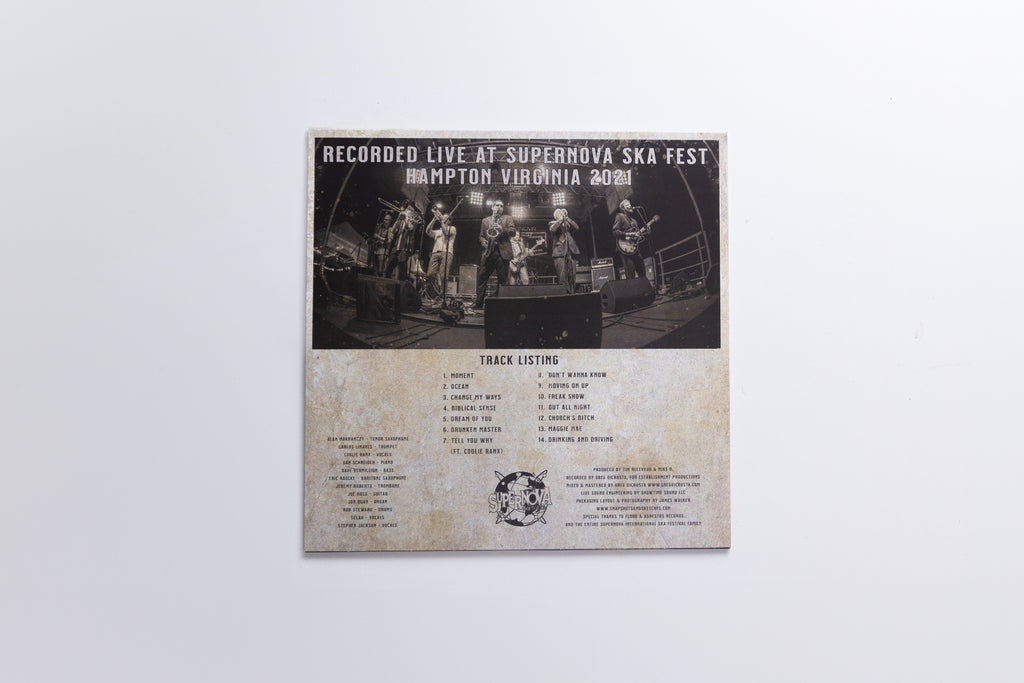 A square printed track listing or booklet page for the band Superhoos, showing a black-and-white live performance photo at the top and track listings below on a weathered beige background, photographed against a light gray wall.