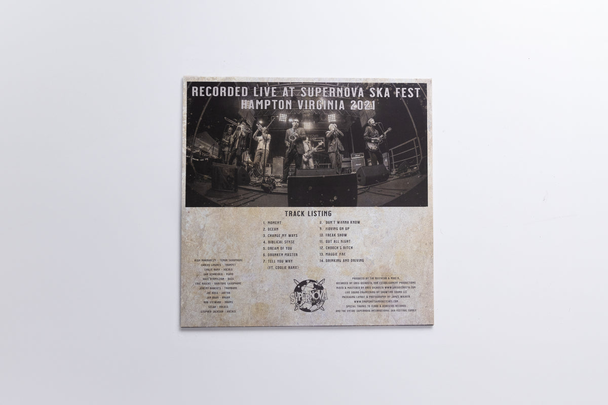 A square printed track listing or booklet page for the band Superhoos, showing a black-and-white live performance photo at the top and track listings below on a weathered beige background, photographed against a light gray wall.